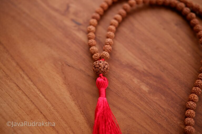 Java Rudraksha mala with red tassel on wood surface